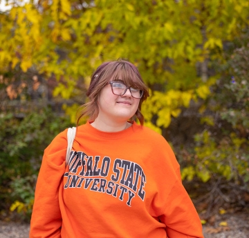 Student standing in front of trees